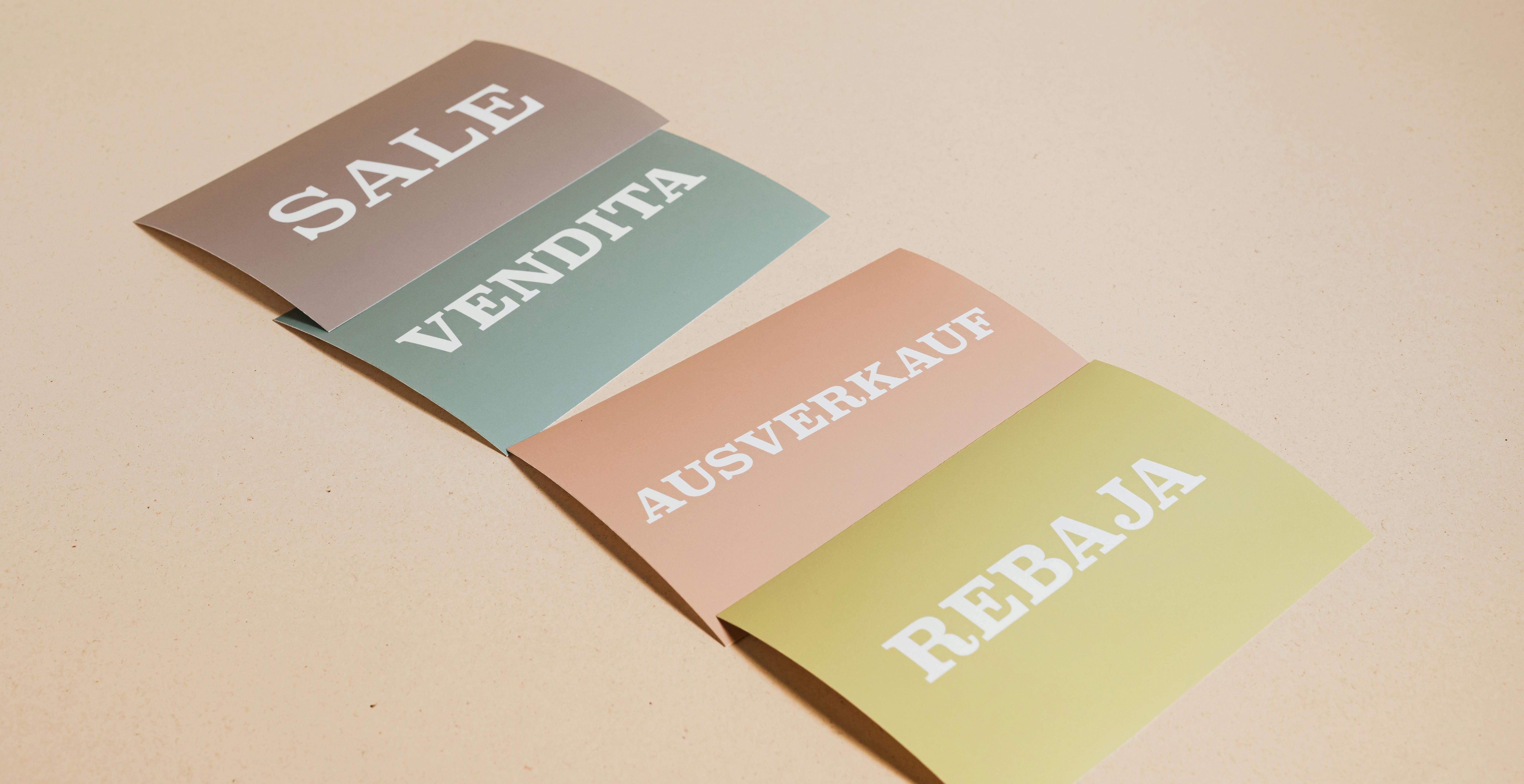 the word "sale" printed on 4 cards, each in a different language