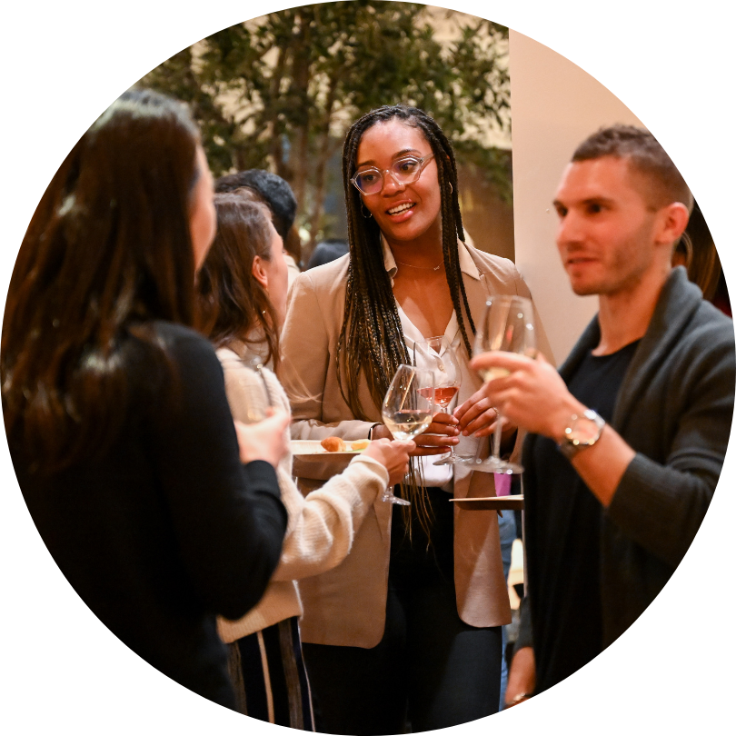 Four people, standing around holding wine glasses