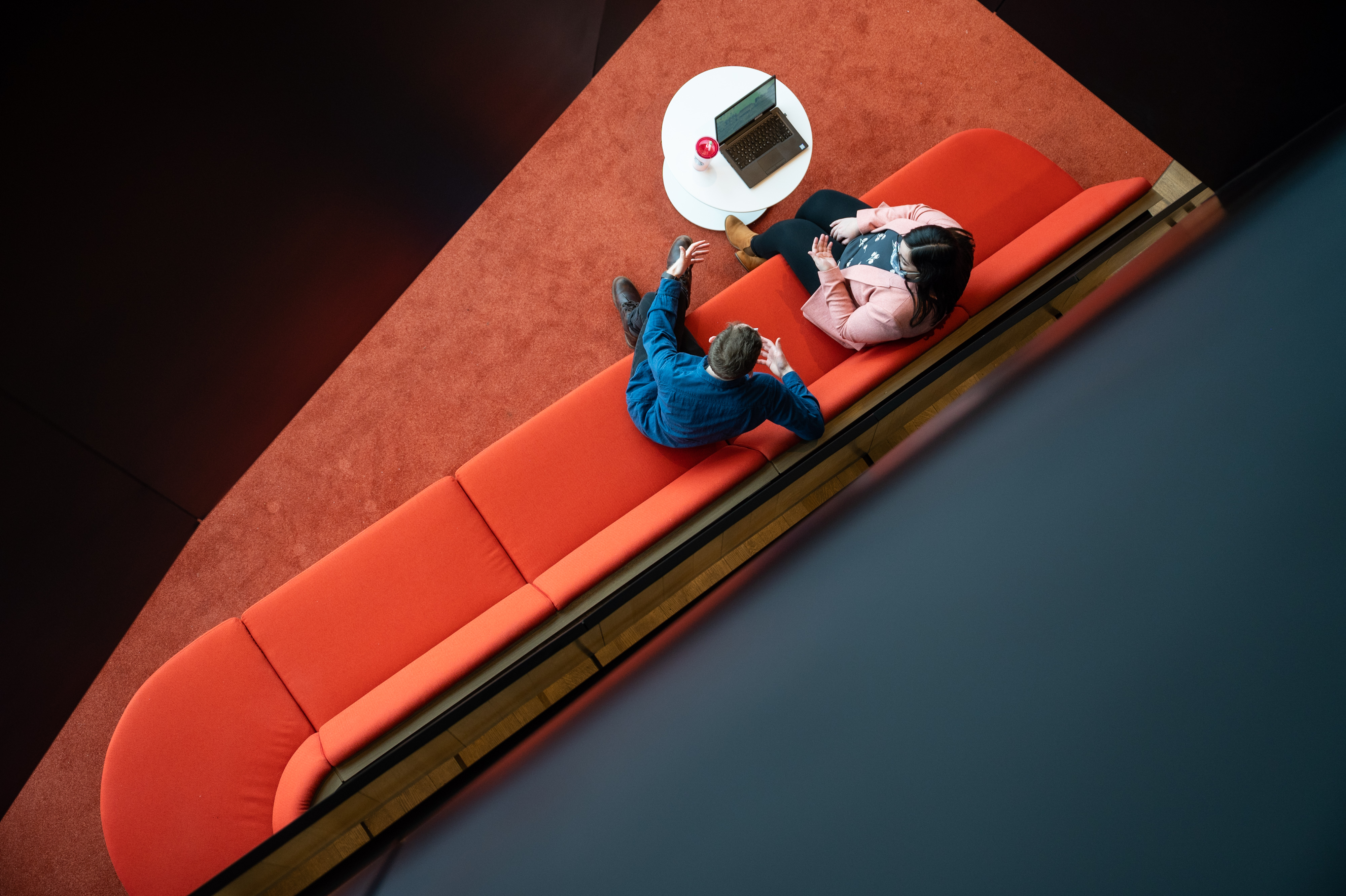 Two people talk together on a couch in the student lounge