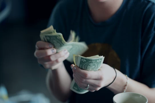 person counting one dollar bills