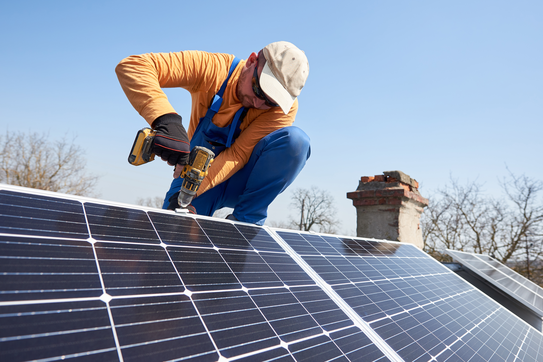 A worker installs solar panels on a roof