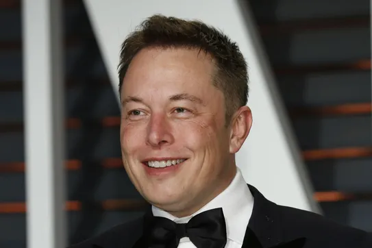 Elon Musk in a tuxedo, grinning