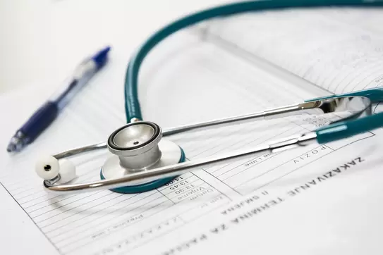 Stethoscope and pen sitting on some paper forms