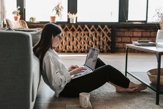 Jobseeker working at home, sitting on the floor with a laptop and a cup of coffee