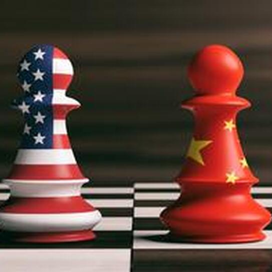 Two chess pieces, one with an American flag and one with a Chinese flag